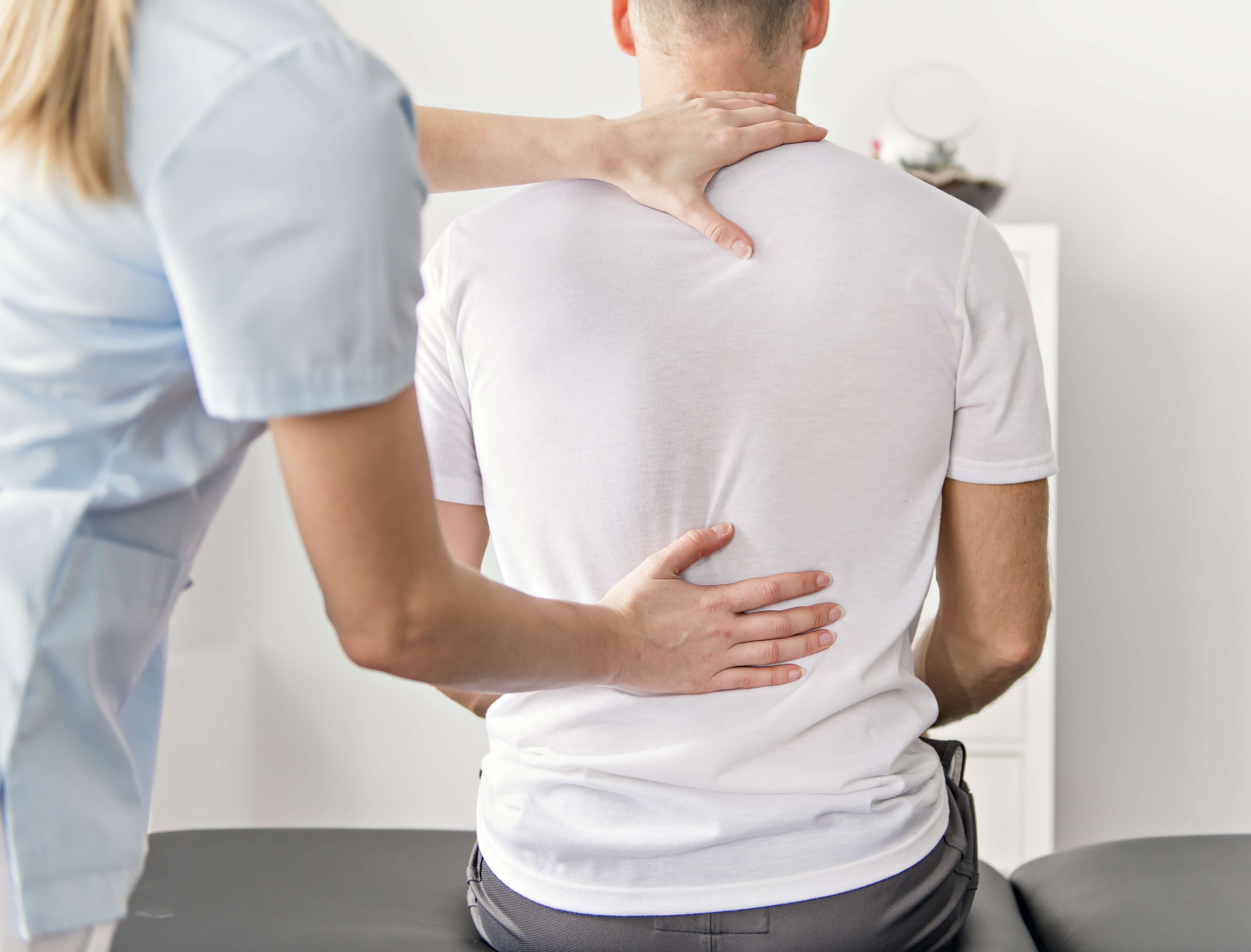 læge, der vurderer sin patient for inflammatoriske lændesmerter