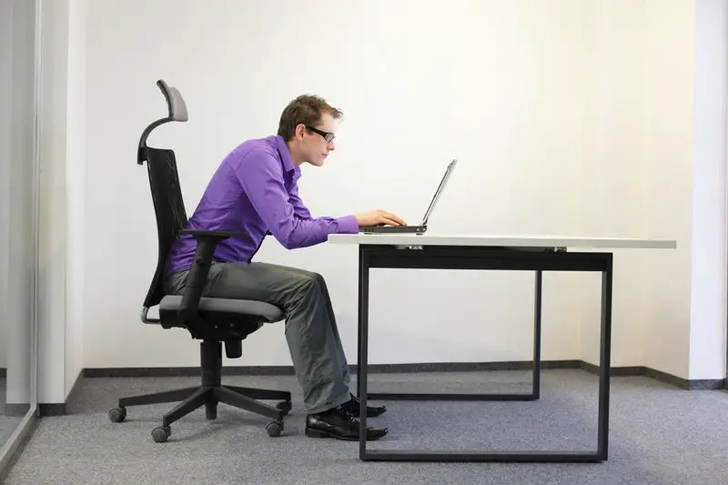 man having a slouched posture in front of his computer