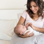 Madre joven con el bebé en la cama